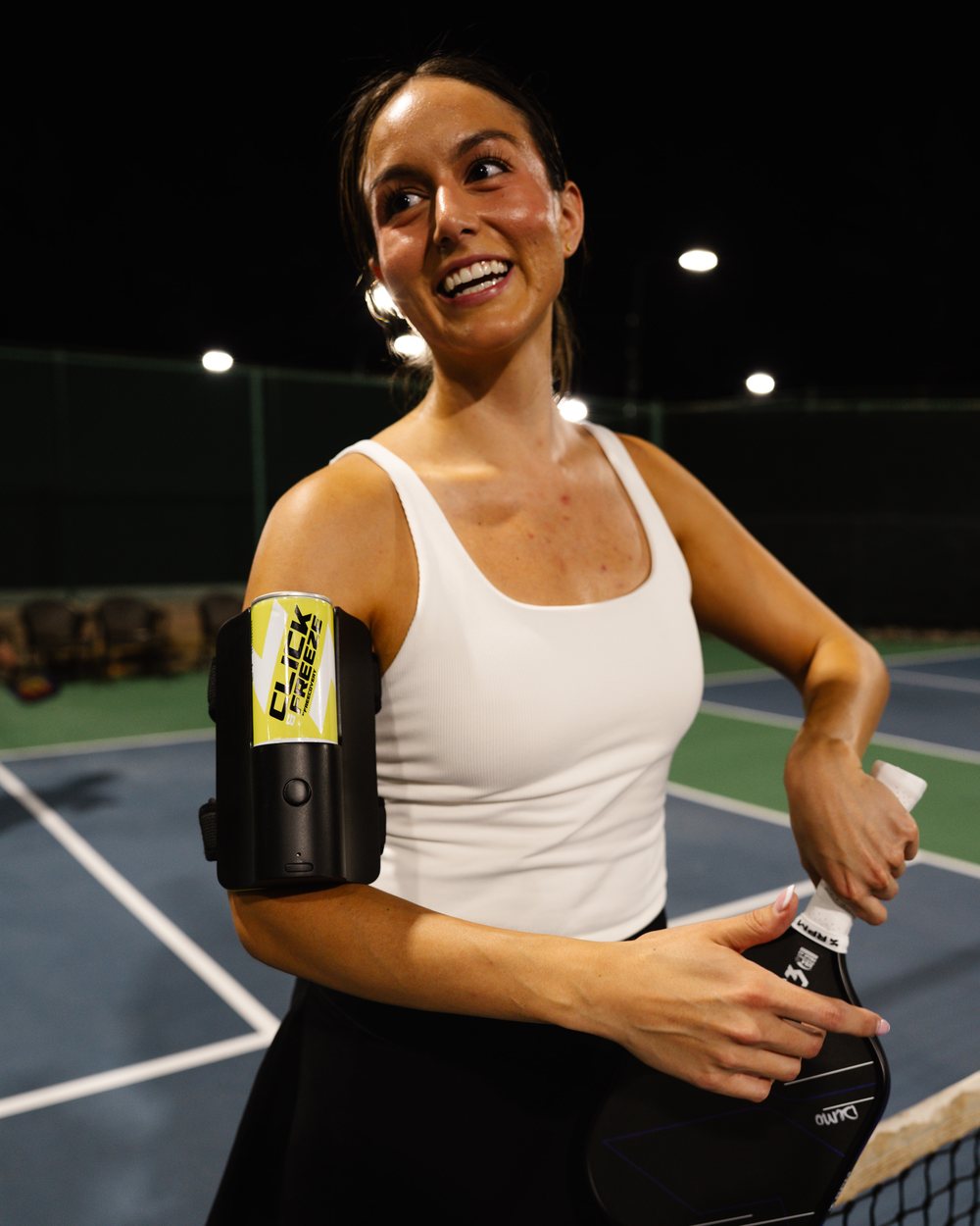 Pickleball player smiling at the net, wearing Click & Freeze on her arm